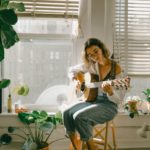 young woman playing guitar in a sunlit room