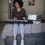 young woman playing keyboards and singing in her bedroom