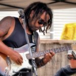 Black man with dreadlocks playing electric guitar