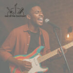 young black man playing electric guitar and singing at an open mic