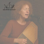 red-haired woman singing and playing autoharp