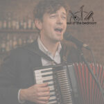 man playing accordion and singing into a microphone