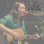 young woman playing guitar and singing into a microphone