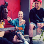 A black musician, a female skinhead and a dude wearing a cap
