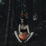 woman in goth gear holding a pumpkin